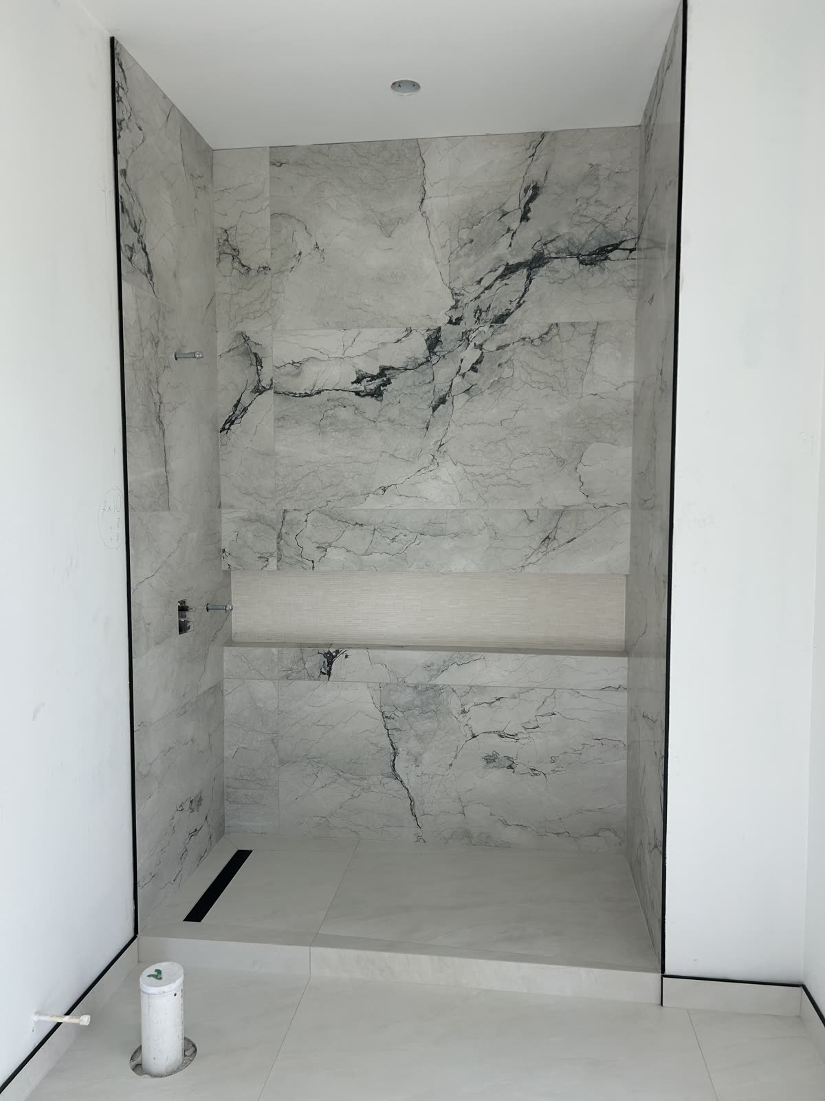 Full-height marble-look porcelain tile shower surround with built-in bench and linear drain